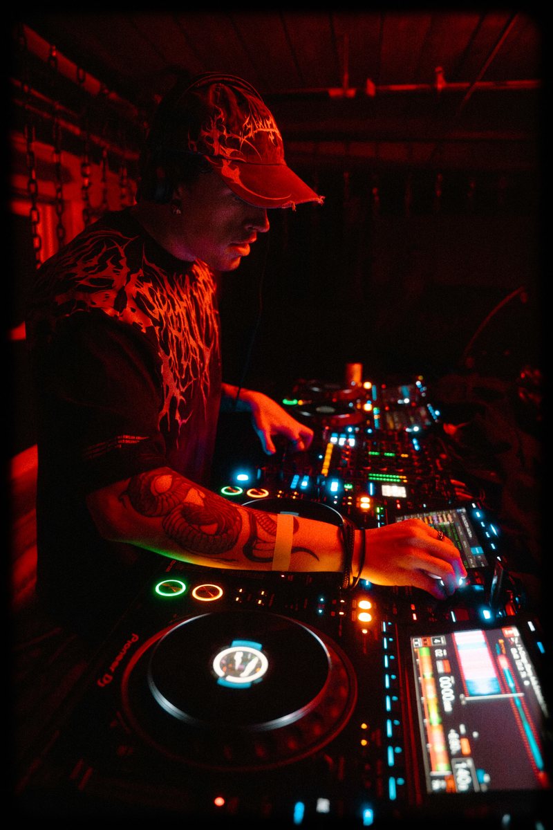 ryzl at the decks in the red booth, under the chains